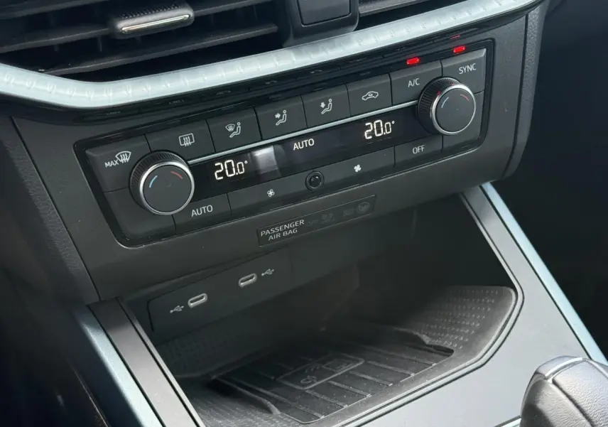 Vue rapprochée de la console centrale du SEAT Arona 2025, avec commandes climatisation et ports USB visibles.