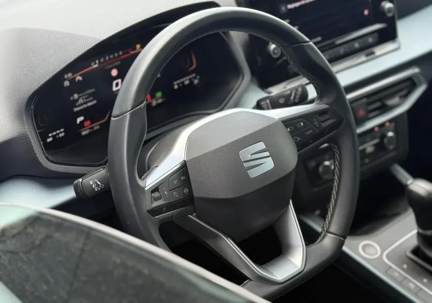 Vue rapprochée du volant noir et du tableau de bord digital du SEAT Arona 2025, avec console centrale visible.