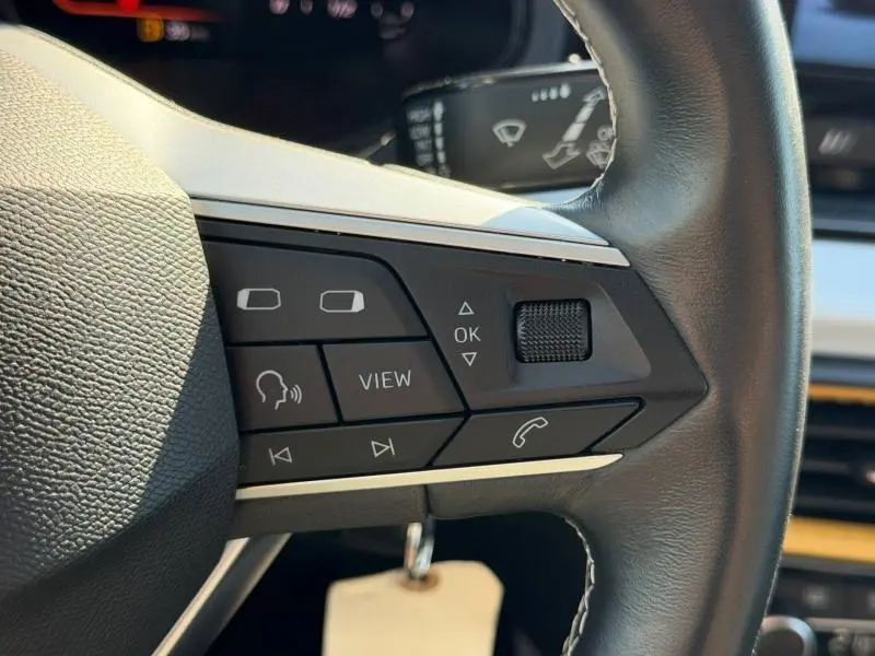 Gros plan sur les commandes multifonctions à droite du volant cuir du SEAT Arona 2025, intérieur moderne et épuré.
