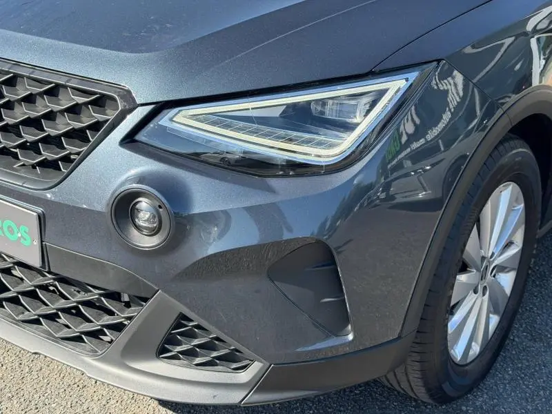 Gros plan sur l'avant droit du SEAT Arona gris Magnétique Métal, mettant en valeur le phare LED et la calandre.