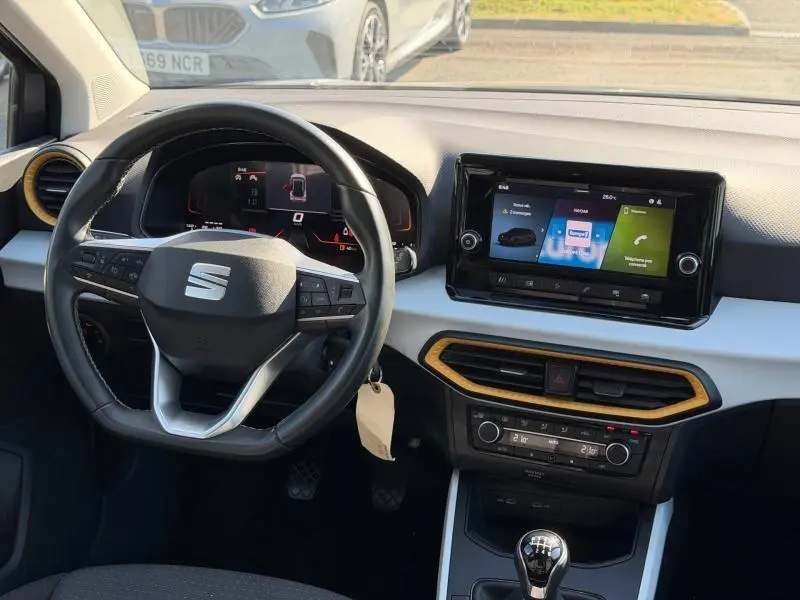 Vue intérieure frontale du tableau de bord du SEAT Arona gris avec volant cuir multifonction et écran tactile central.
