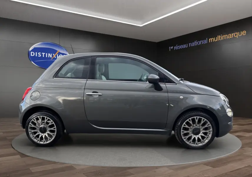 Profil droit de la Fiat 500 gris foncé 2020 avec jantes alliage et rétroviseurs noirs en showroom.