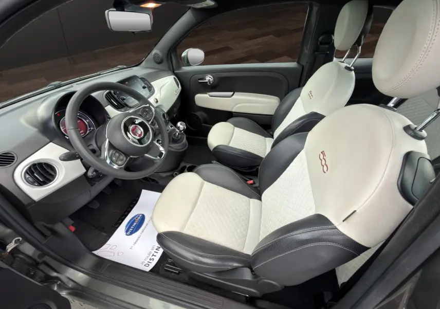 Vue intérieure côté conducteur de la Fiat 500 2020, sièges cuir bicolores beige et noir avec logo 500 brodé.