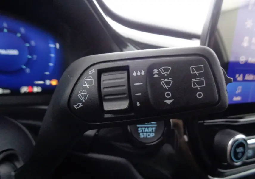 Gros plan sur la commande d’essuie-glace du Ford Puma blanc 2022, avec tableau de bord et bouton start/stop visibles.