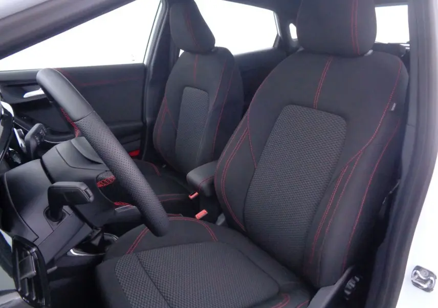 Intérieur avant du Ford Puma blanc 2022, sièges noirs avec surpiqûres rouges et volant en cuir perforé.