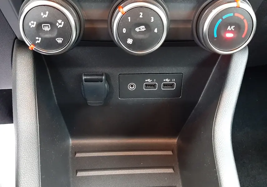 Vue rapprochée des commandes de climatisation et des ports USB du tableau de bord de la Renault Clio V gris schiste 2025.