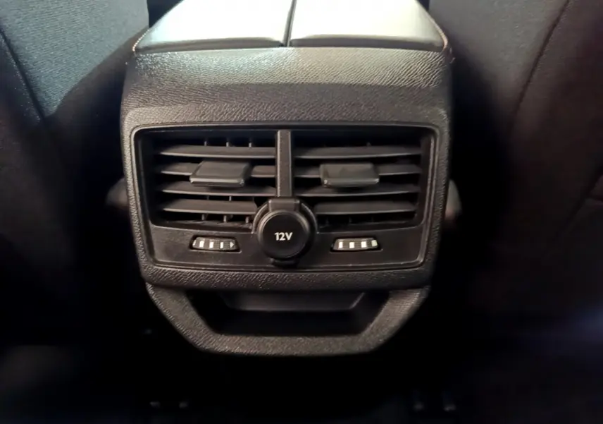 Vue rapprochée des aérateurs arrière noirs et prise 12V intégrée sur la console centrale du Peugeot 3008 blanc 2020.