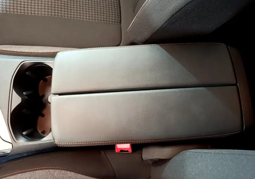 Accoudoir central noir avec surpiqûres rouges et porte-gobelets dans l'habitacle du Peugeot 3008 blanc 2020.