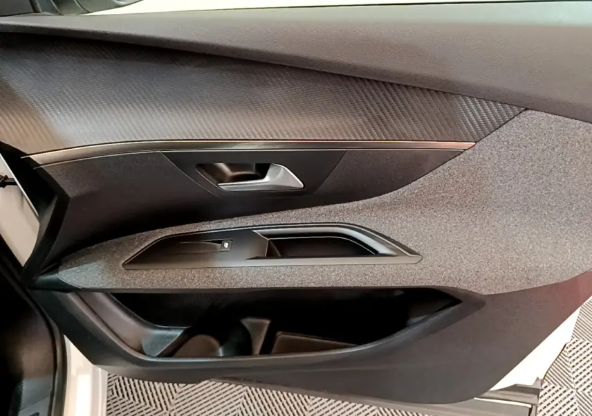 Détail de la porte côté gauche intérieure du Peugeot 3008 blanc, avec poignée et commande de vitre noire.