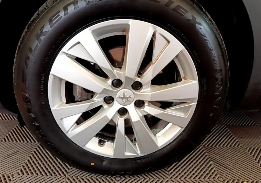 Gros plan sur la jante alliage argentée et pneu noir d'un Peugeot 3008 blanc, avec logo lion au centre.