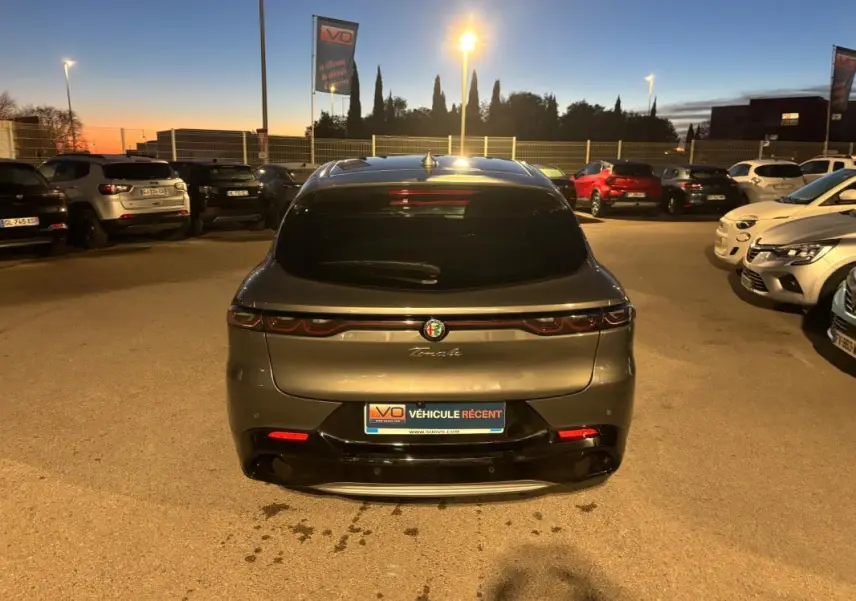 Vue arrière d'une Alfa Romeo Tonale gris métallisé 2023 avec feux LED et logo centré au crépuscule.