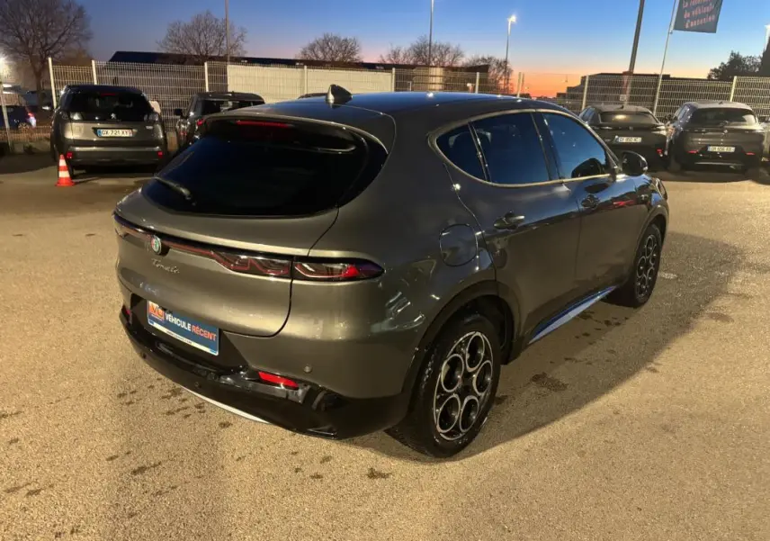 Vue 3/4 arrière droite d'une Alfa Romeo Tonale gris métallisé 2023 avec jantes alliage 18 pouces, en extérieur au crépuscule.