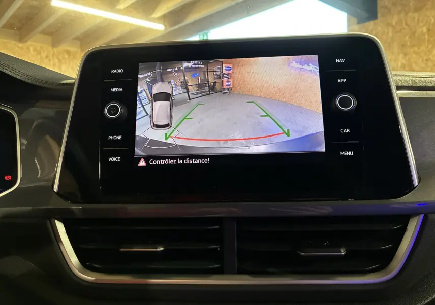 Écran central affichant la caméra de recul avec guidage de trajectoire dans un Volkswagen T-Roc gris, vue intérieure.