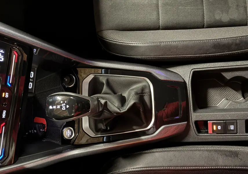 Gros plan sur la console centrale du Volkswagen T-Roc gris 2023, mettant en valeur le levier de vitesse automatique et les commandes environnantes.
