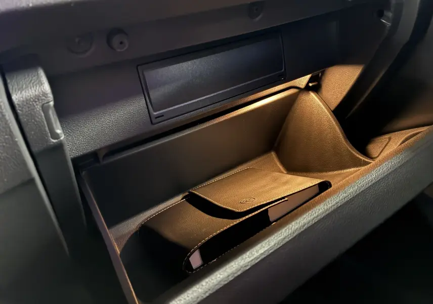 Vue rapprochée de la boîte à gants ouverte du Volkswagen T-Roc 2023, avec un étui en cuir noir à l'intérieur.