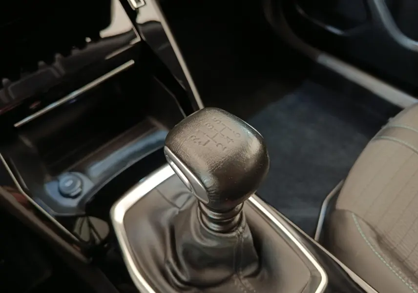 Gros plan sur le levier de vitesses manuel en cuir noir dans l’habitacle d’une Peugeot 2008 bleu.