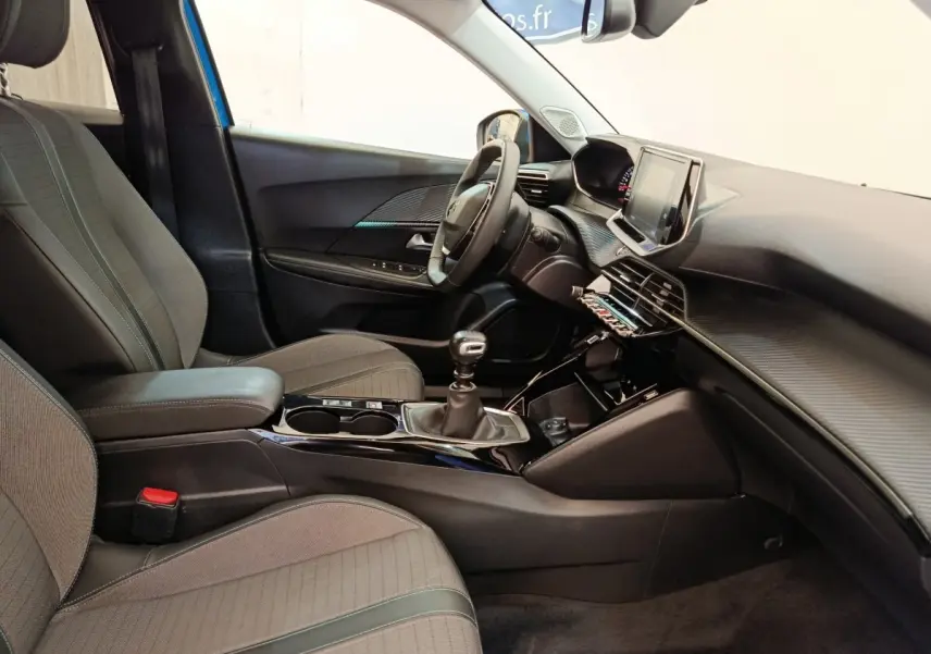 Vue intérieure côté conducteur du Peugeot 2008 bleu 2021, avec volant cuir multifonctions et tableau de bord moderne.