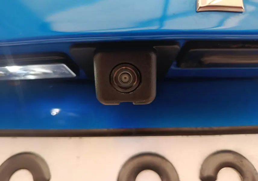 Gros plan sur la caméra de recul noire intégrée au hayon bleu d'une Peugeot 2008 PureTech 100 S&S Allure Pack.