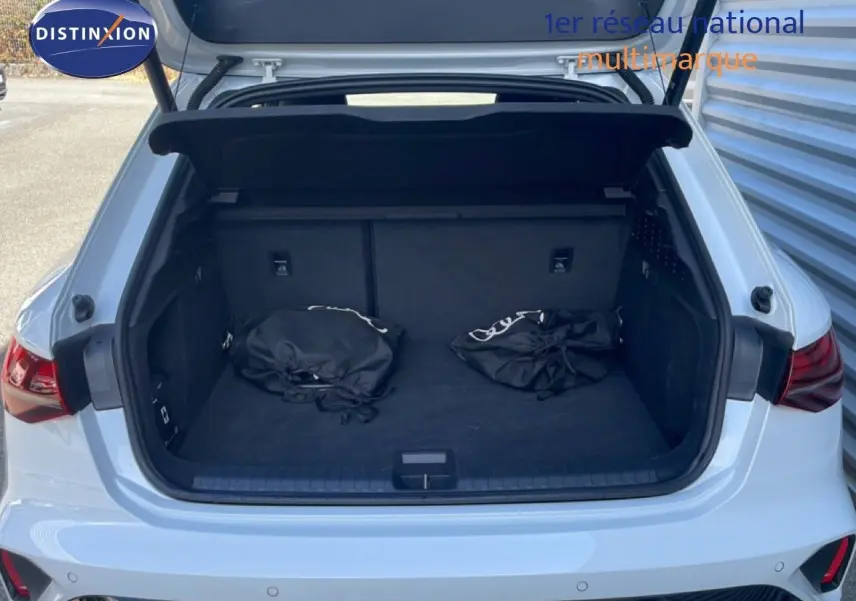 Coffre ouvert vu de l'arrière d'une Audi A3 Sportback 40 TFSIe blanc Ibis avec deux sacs noirs à l'intérieur.