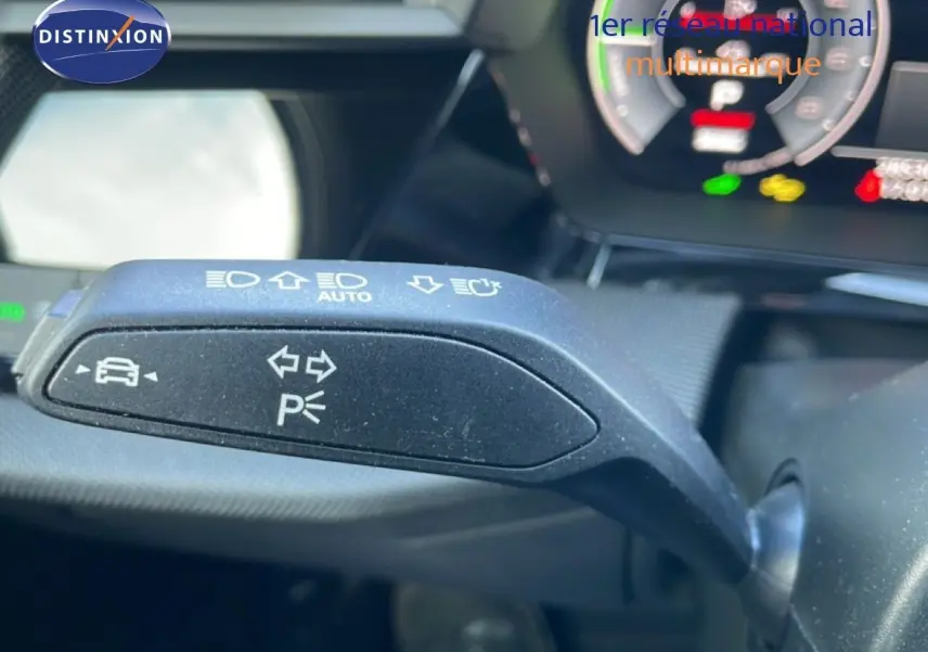Gros plan sur la commande de clignotant et feux automatiques de l'Audi A3 Sportback blanc Ibis 2025, intérieur gris-noir.