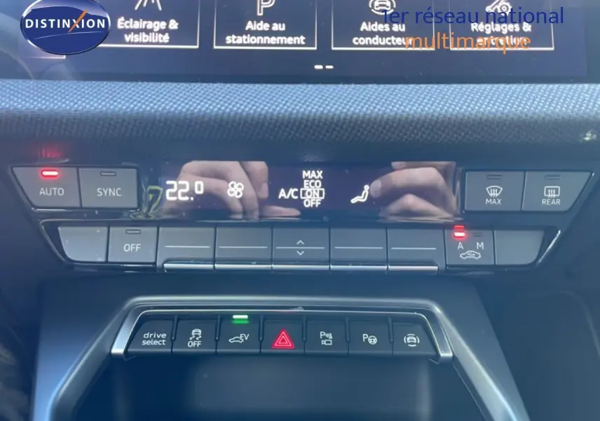 Gros plan sur la console centrale de l'Audi A3 Sportback blanc Ibis 2025, montrant les commandes climatisation et aides à la conduite.