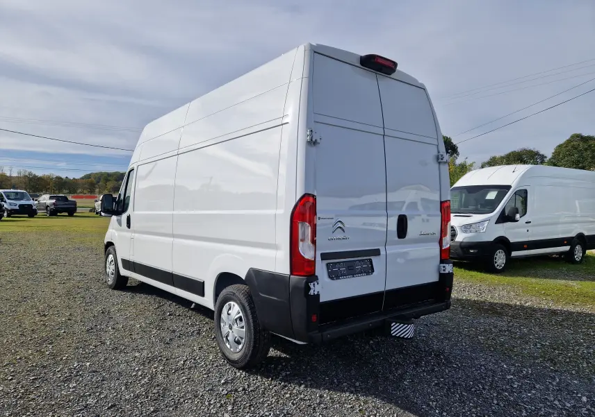 Vue 3/4 arrière droite d'un utilitaire Citroën Jumper blanc L3H3 2023 avec hayon et feux arrière rouges.