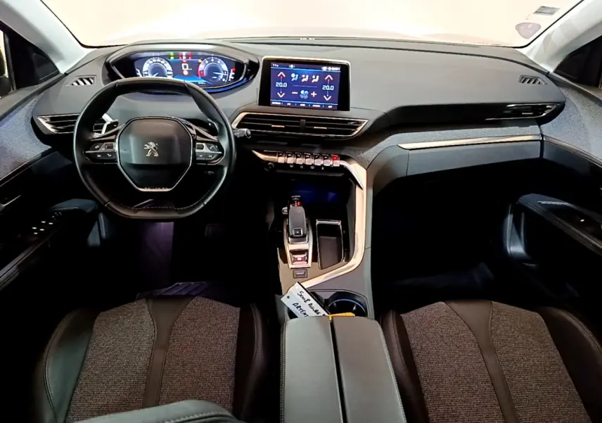 Intérieur du Peugeot 5008 gris clair, vue frontale sur le tableau de bord avec écran tactile et volant compact cuir.
