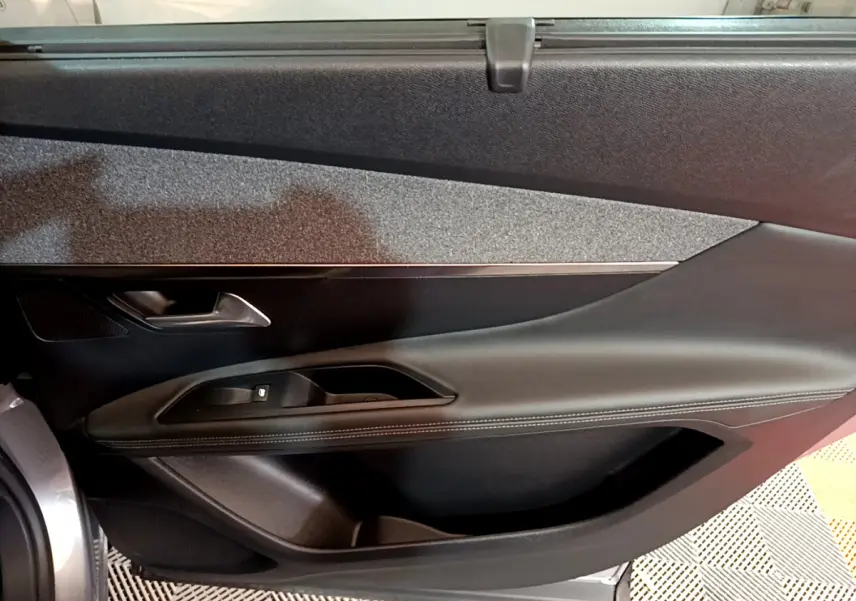 Vue intérieure côté gauche de la porte avant gris clair du Peugeot 5008 avec garniture noire et surpiqûres blanches.