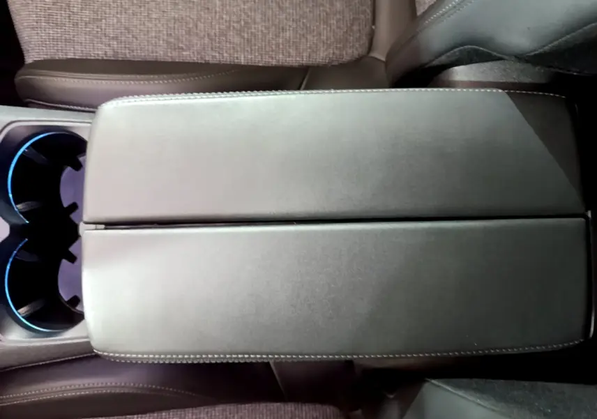 Vue rapprochée de l'accoudoir central en cuir noir et des porte-gobelets éclairés du Peugeot 5008 gris clair 2020.