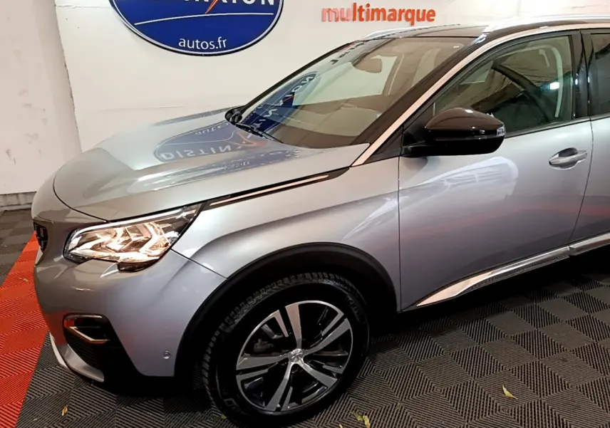 Vue 3/4 avant droit d'un Peugeot 5008 gris clair avec phares LED allumés et jantes alliage bicolores.