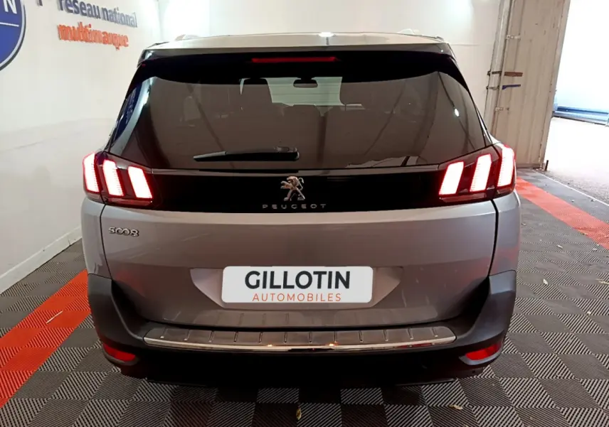 Vue arrière d'un Peugeot 5008 gris clair avec feux LED caractéristiques et logo au centre du hayon.