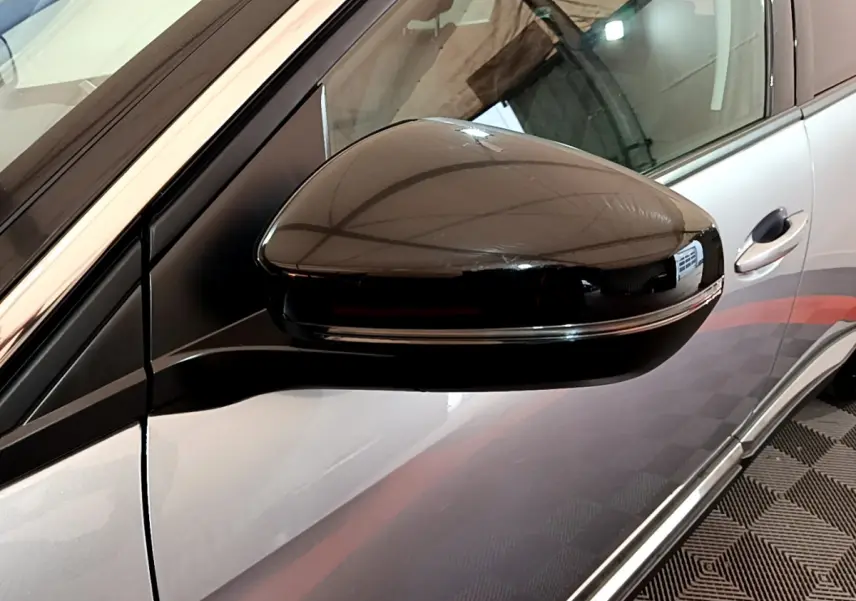 Rétroviseur côté gauche noir brillant sur Peugeot 5008 gris clair, avec poignée de porte visible en arrière-plan.