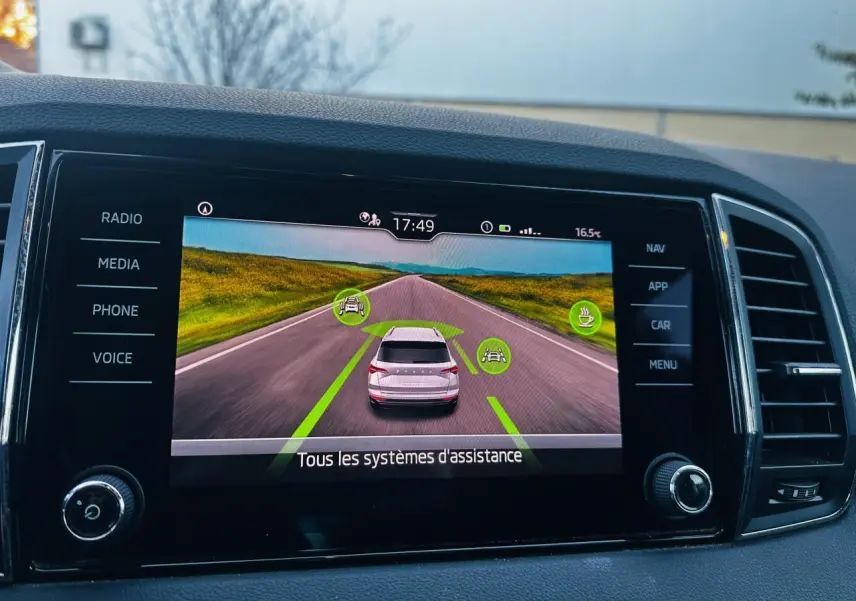 Écran tactile intérieur montrant l'aide au stationnement avec vue arrière virtuelle du Skoda Karoq blanc.