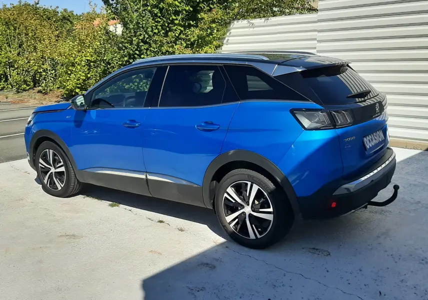 Peugeot 3008 bleu Vertigo avec toit noir, vue 3/4 arrière côté gauche, stationné sur sol clair en extérieur.