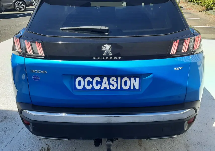 Vue arrière d'un Peugeot 3008 bleu Vertigo avec toit noir, badge GT et attelage visible sur parking.