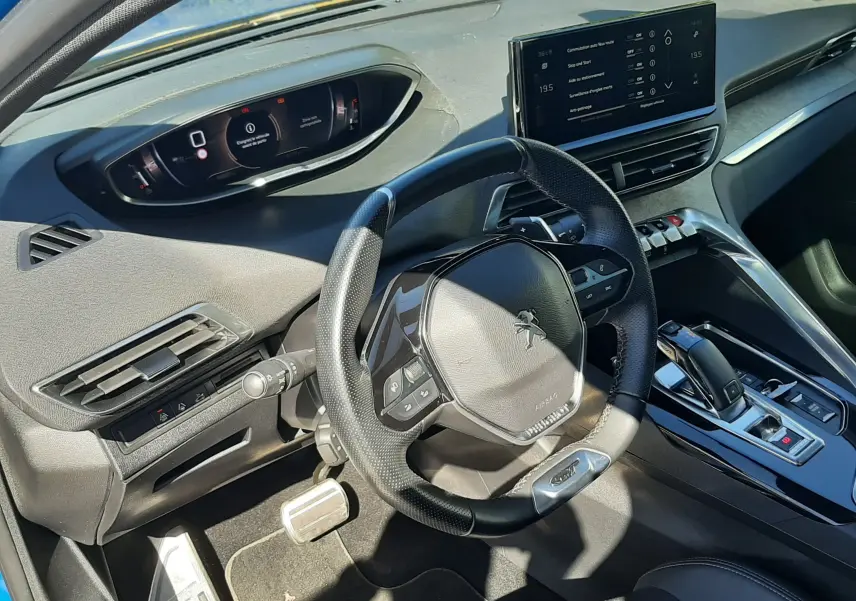 Vue intérieure côté conducteur du Peugeot 3008 2023, volant compact, tableau de bord numérique et écran central tactile.