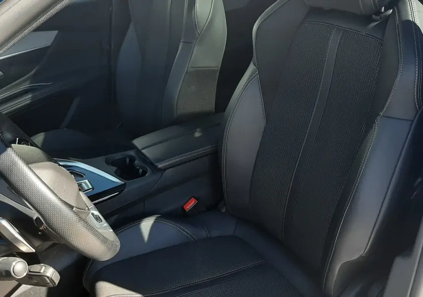 Vue intérieure côté conducteur du Peugeot 3008 2023, sièges en cuir noir avec surpiqûres blanches et console centrale moderne.