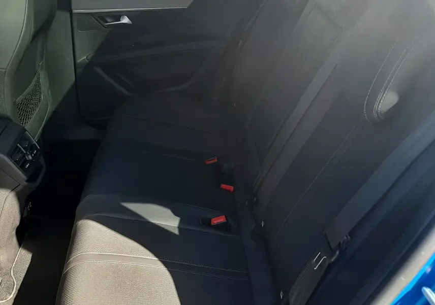 Vue intérieure côté droit des sièges arrière noirs du Peugeot 3008 2023, avec ceinture de sécurité et porte ouverte bleu Vertigo.