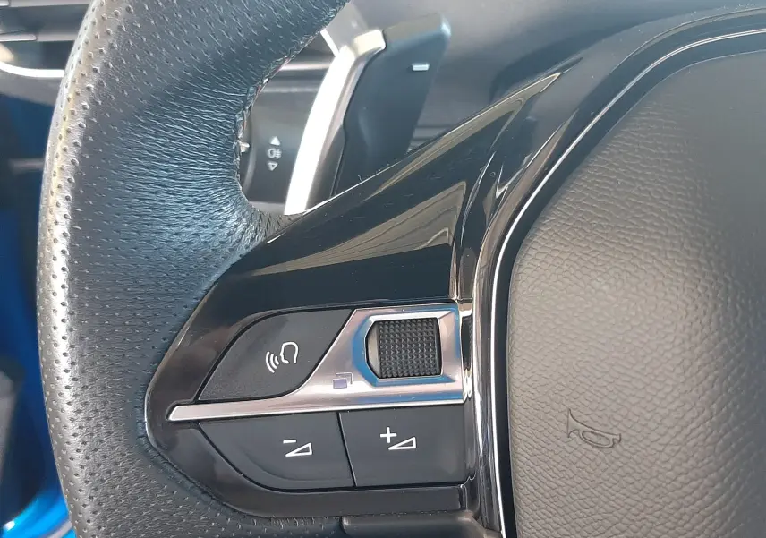 Gros plan sur les commandes au volant côté gauche du Peugeot 3008 2023 bleu Vertigo avec finition Black Diamond.