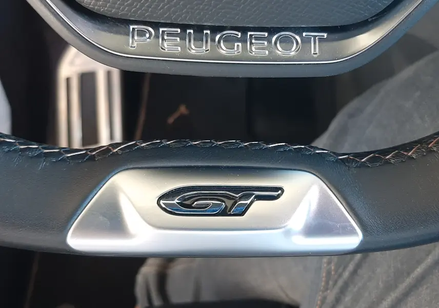 Gros plan sur le volant noir du Peugeot 3008 GT 2023 avec logo GT et inscription Peugeot sur l'airbag.