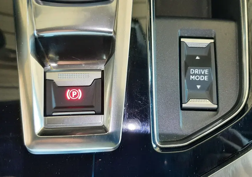 Gros plan sur la console centrale du Peugeot 3008 bleu Vertigo, avec bouton frein à main électronique et mode de conduite.