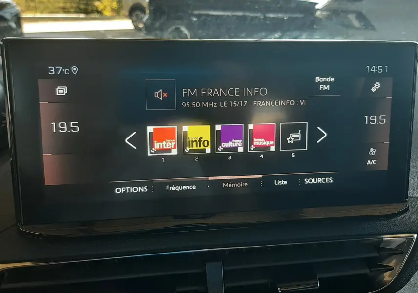 Écran tactile central du Peugeot 3008 2023 affichant les stations radio FM avec commande de climatisation à 19,5°C.