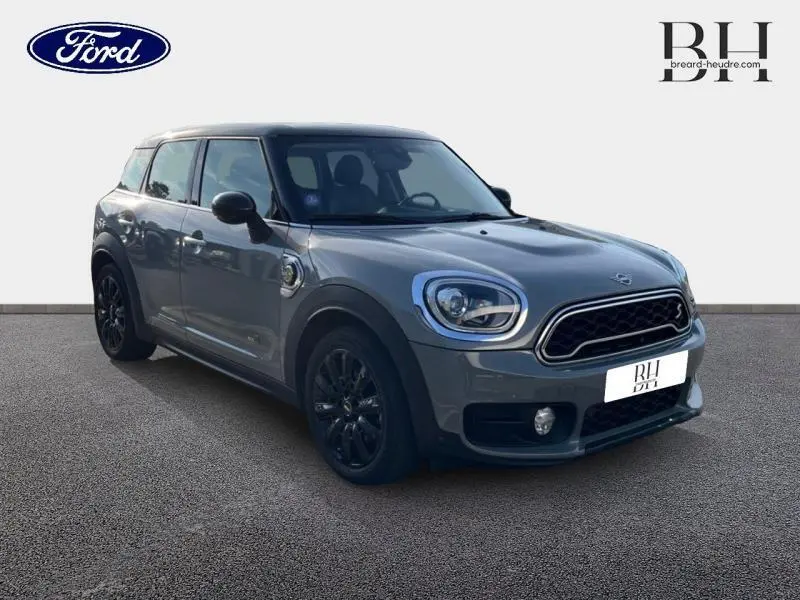 Vue 3/4 avant d'une MINI COUNTRYMAN Cooper SE hybride rechargeable en Moonwalk Grey avec jantes noires et toit panoramique.