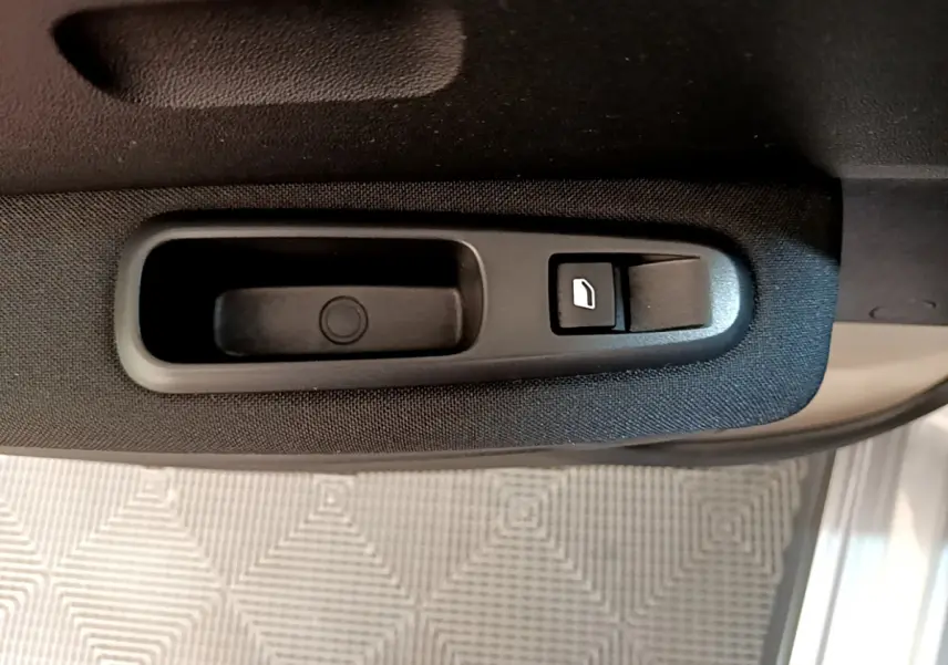 Gros plan sur la commande de lève-vitre côté conducteur d'une Citroën C3 gris clair de 2019.