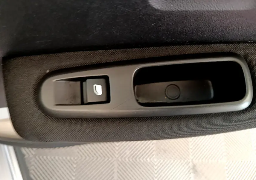 Gros plan sur la commande de lève-vitre côté conducteur d'une Citroën C3 gris clair 2019.