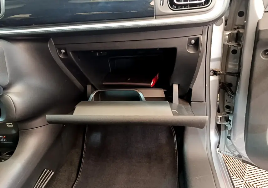 Gros plan sur la boîte à gants ouverte côté passager d'une Citroën C3 gris clair, intérieur noir.