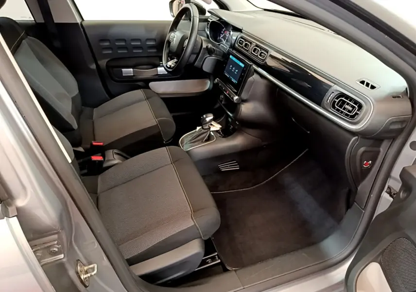 Vue intérieure côté conducteur de la Citroën C3 gris clair 2019 avec tableau de bord moderne et sièges tissu noirs.