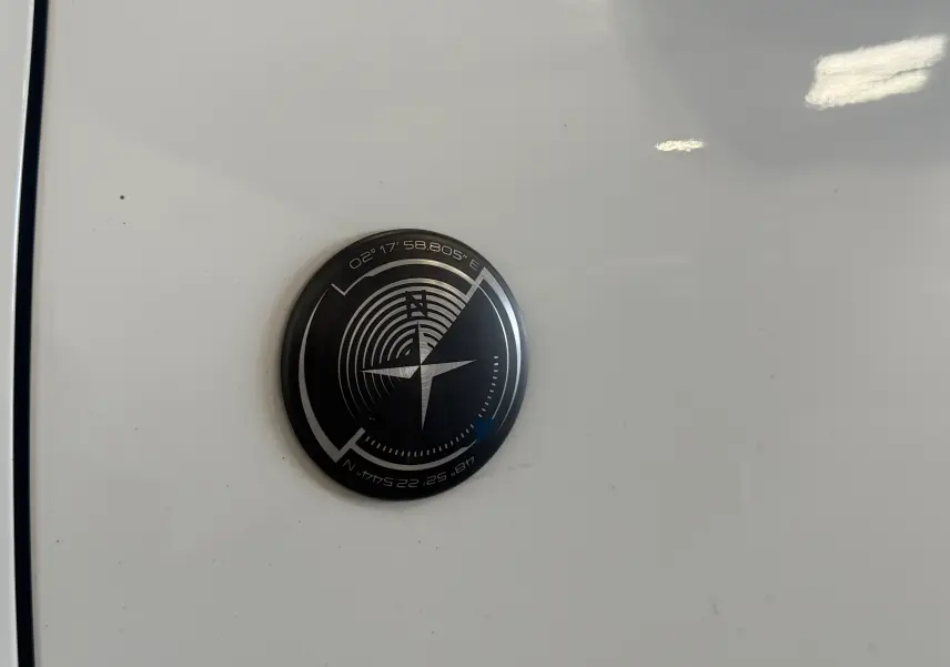 Gros plan sur l'écusson boussole noir et argent sur la carrosserie blanche d'un Peugeot 2008 Crossway 2018.