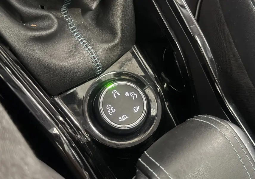Gros plan sur la molette de sélection des modes de conduite du Peugeot 2008 blanc, avec coutures bleues visibles.