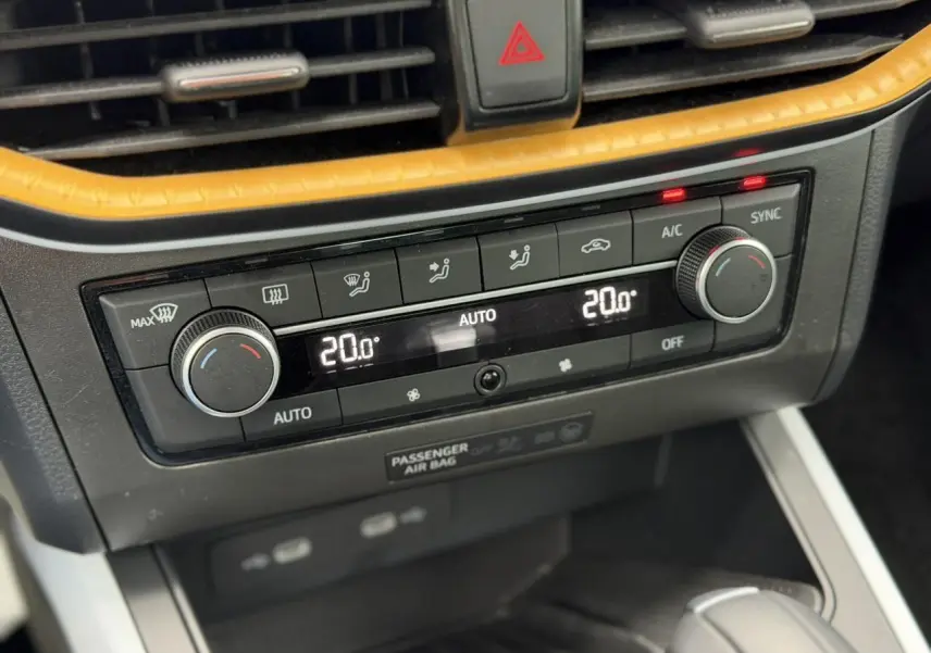 Gros plan sur la console centrale du SEAT Arona blanc, montrant la climatisation automatique bi-zone réglée à 20°C.